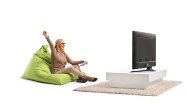 Beyaz arka planda izole edilmiş, televizyon karşısında video oyunu oynayan orta yaşlı bir kadın.