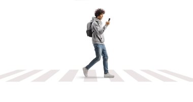 Bir öğrenci sırt çantası taşıyor ve beyaz arka planda izole edilmiş akıllı bir telefonla yaya geçidinde yürüyor.