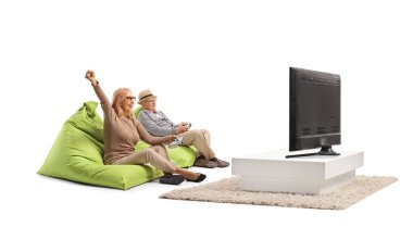Olgun erkek ve kadın, beyaz arka planda izole bir şekilde televizyon karşısında oyun oynuyor.