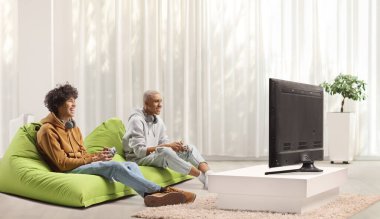 Bir apartmanda TV karşısında video oyunu oynayan arkadaşlar