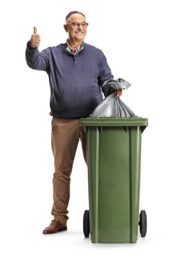 Gülümseyen olgun bir adam çöp kutusuna çöp torbası atıyor ve beyaz arka planda izole edilmiş, el kol hareketi yapıyor.