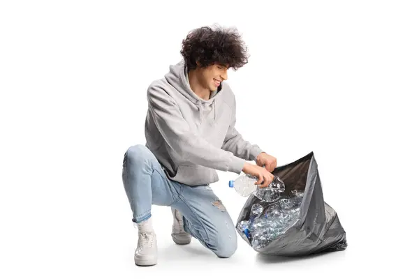 白い背景に隔離された黒い廃棄物袋でプラスチックびんを集める若者 — ストック写真