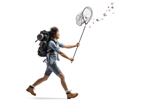 Полнометражный снимок молодого человека с рюкзаком, бегущего за бабочками с ловящей сетью, изолированной на белом фоне    