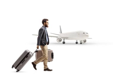 Bavullu bir adamın beyaz arka planda izole edilmiş bir uçağa doğru yürüyüşünün tam boy profil fotoğrafı.