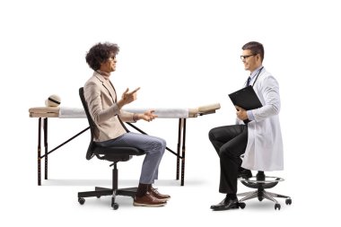Sandalyede oturan ve beyaz arka planda izole edilmiş bir doktorla konuşan bir adamın profil fotoğrafı.