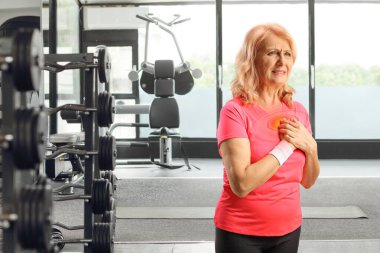 Orta yaşlı bir kadın spor salonunda göğsünde baskı hissediyor. 