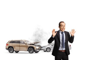 Shocked businessman gesturing with hands in front of a car crash isolted on white background clipart
