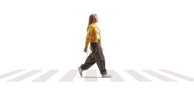 Beyaz arka planda izole bir şekilde yaya geçidinde yürüyen modaya uygun genç bir kızın tam boy profil çekimi.