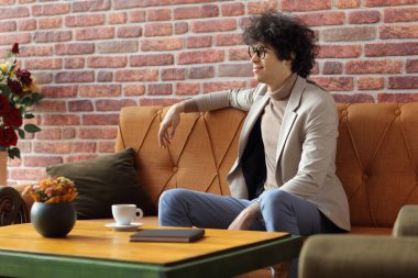 Genç adam kafede kahve içiyor ve dinleniyor, dinleniyor.