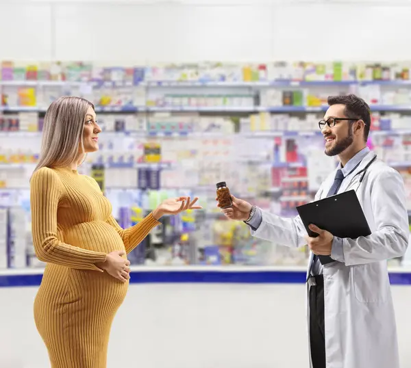 薬局内の妊婦に薬を与える医師 — ストック写真