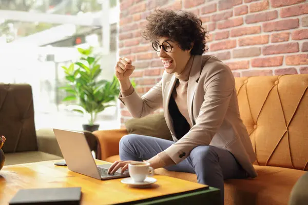 stock image Happy young man sitting in a cafe and using a laptop computer 