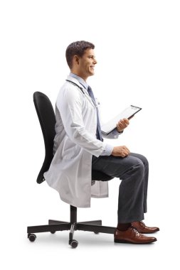 Ofis sandalyesinde oturan ve elinde beyaz arka planda izole edilmiş bir dosya tutan gülümseyen erkek doktor.