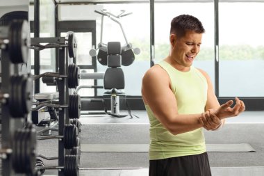 Spor salonunda bileğini tutan genç bir adam, spor sakatlığı konsepti.