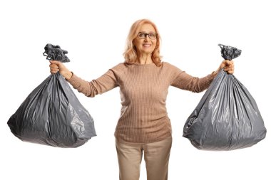 Beyaz arka planda siyah çöp torbaları taşıyan gülümseyen olgun bir kadın.
