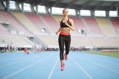 Spor sahasında koşan bir bayan sporcu.