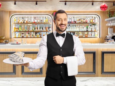 Bir barın önünde içinde yığınla para olan bir tabak tutan sunucu