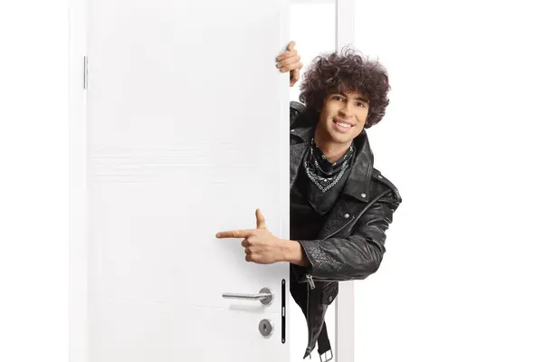 ドアの後ろに立っている黒い革のジャケットの若い男と指す ストック画像