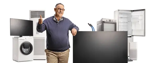 成熟した男は 白い背景に隔離されたフラットテレビ画面と家庭電化製品の隣に親指を振る ストック画像