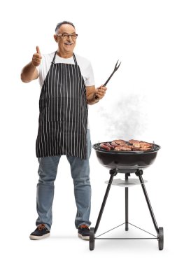 Portatif ızgaranın yanında elinde çatal ve beyaz arka planda izole edilmiş el kol hareketi yapan olgun bir adam.