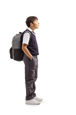 Üniformalı bir çocuğun, elleri ceplerinde ve beyaz arka planda izole bir şekilde dikilirken tam boy profil fotoğrafı.