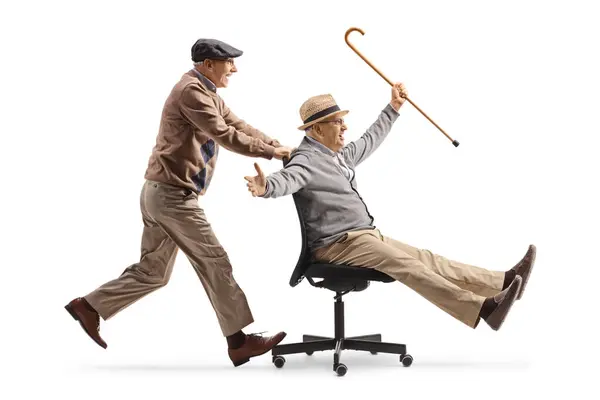 Oudere Man Duwen Een Vriend Zit Een Bureaustoel Wielen Geïsoleerd Stockfoto