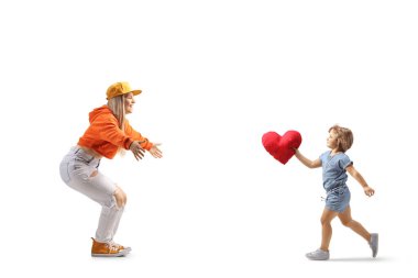 Küçük bir kızın kalp tutarken ve beyaz arka planda izole edilmiş genç bir kadınla tanışırken tam boy profil fotoğrafı.