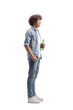 Beyaz arka planda izole edilmiş bira şişesini tutan kıvırcık saçlı genç bir adamın tam boy fotoğrafı.