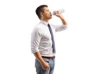 Beyaz arka planda izole edilmiş plastik bir şişeden su içen genç adam.
