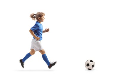 Futbol formalı bir kızın beyaz arka planda izole edilmiş bir topun peşinden koşarken tam boy profil fotoğrafı.