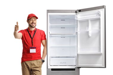 Satış elemanı buzdolabına yaslanıyor ve beyaz arka planda izole edilmiş baş parmağını gösteriyor.