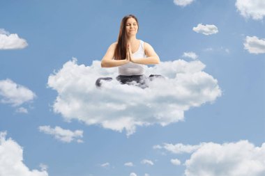 Bulutların üzerinde yüzen ve meditasyon yapan pijamalı genç bir kadın. 