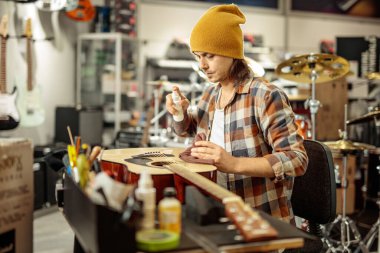 Adam atölyede akustik gitar püskürtüyor.