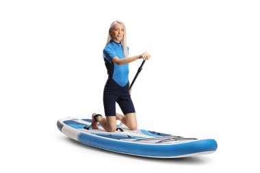 Dalış kıyafetli bir kadın, beyaz arka planda izole edilmiş bir yemek masasının üzerinde diz çöküyor.