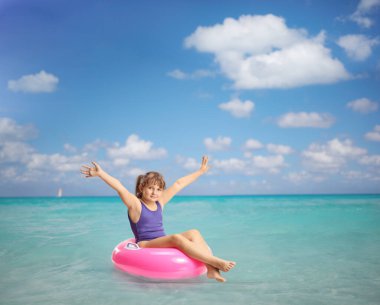 Denizde yüzen bir yüzükte oturan mutlu çocuk