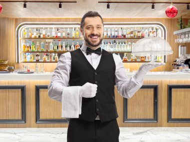 Barda elinde boş bir kek tabağı tutan gülümseyen garson.