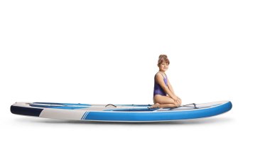 Beyaz arka planda izole edilmiş bir SUP 'de oturan küçük bir kızın tam boy profil fotoğrafı.