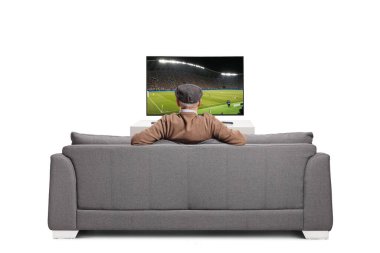 Emekli, televizyonda futbol seyrediyor ve beyaz arka planda izole bir koltukta oturuyor.