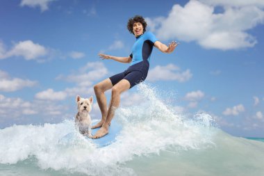 Dalgıç kıyafetli bir adam köpekle sörf tahtası sürüyor.