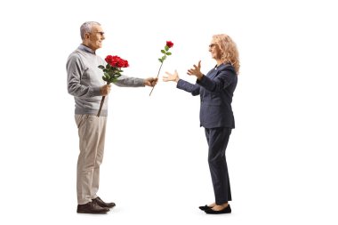 Yaşlı bir adamın beyaz arka planda izole edilmiş bir kadına kırmızı gül verirken tam boy profil fotoğrafı.