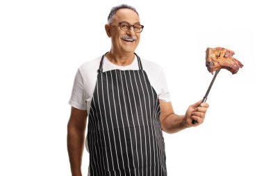 Beyaz arka planda pişmiş biftek tutan olgun bir adam.