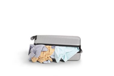 Düzenlenmemiş bavul ve beyaz arka planda giysiler.