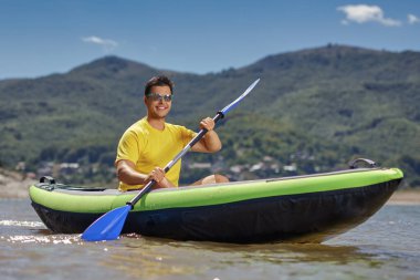 Dağlarla çevrili bir gölde kayak yapan adam. 