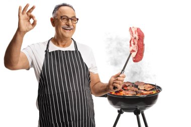 Olgun bir adam bbq hazırlıyor ve beyaz arka planda izole edilmiş sığır filetosu tutuyor.