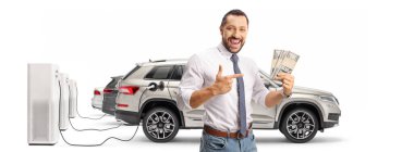 Şarj istasyonunda arabaların önünde para tutan ve beyaz arka planda izole edilmiş bir adamı işaret eden mutlu bir adam.