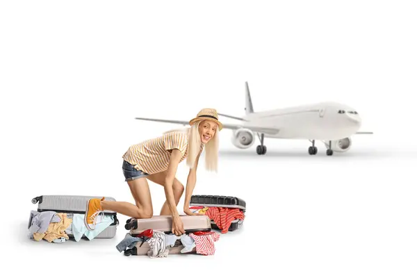 stock image Young woman trying to close overpacked suitcase at the airport isolated on white background