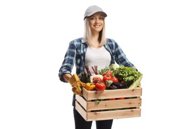 Sebzeli bir sandık taşıyan ve beyaz arka planda sırıtan bir kadın çiftçi.