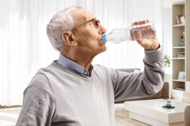 Evdeki şişeden su içen yaşlı bir adamı yakından çek.