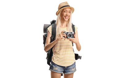 Sırt çantalı heyecanlı genç bir turist beyaz arka planda izole edilmiş bir kamerayla fotoğraf çekiyor.