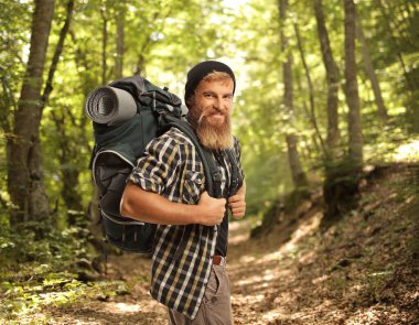Ormanda gülümseyen sırt çantalı neşeli bir yürüyüşçü.