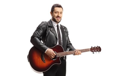 Deri ceketli bir adam beyaz arka planda izole edilmiş akustik bir gitar tutuyor.